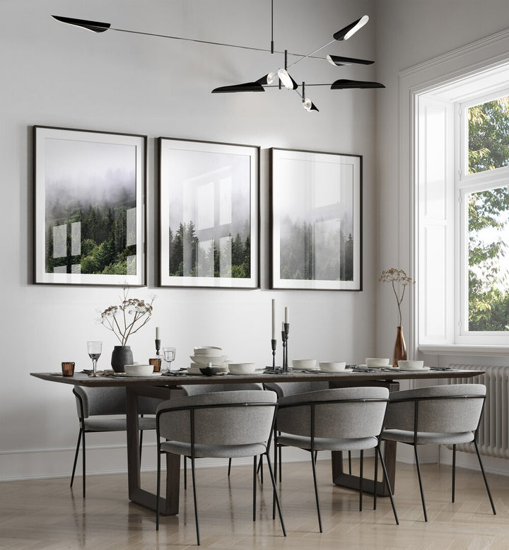 CLOUDY MOUNTAINS, SET OF 3 PAINTINGS adorns a modern dining space, showcasing serene misty forest landscapes.