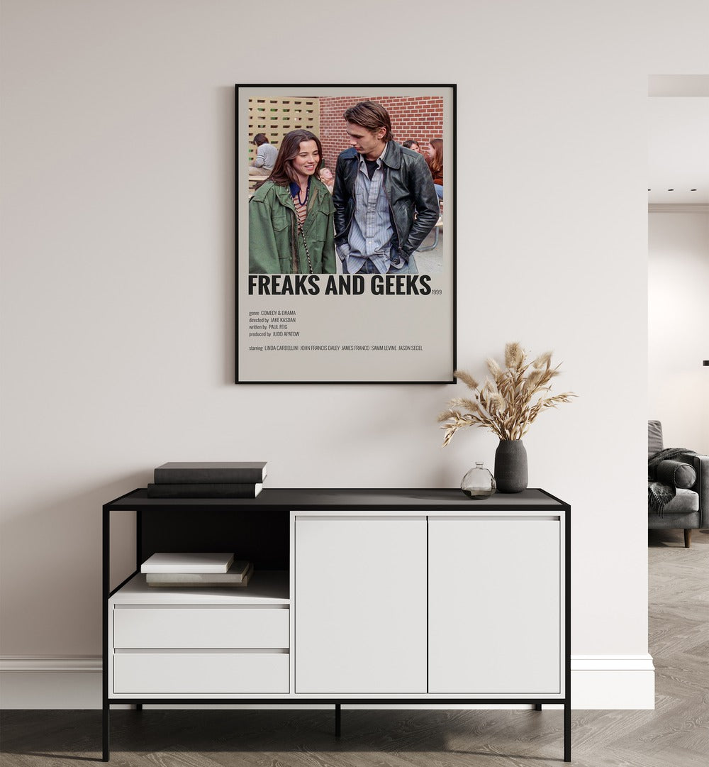 Freaks And Greaks Movie Posters in Black Plain Frame placed on a white wall behind a black and white table