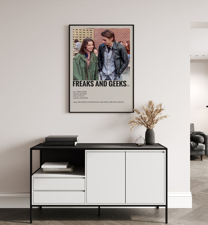 Freaks And Greaks Movie Posters in Black Plain Frame placed on a white wall behind a black and white table