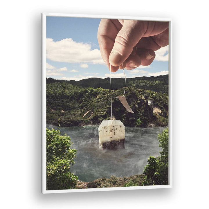 Hand holding a teabag above a serene lake, embodying LAKE AFTERNOON TEA, SURREAL ART PRINTS by Vertigo Artography.
