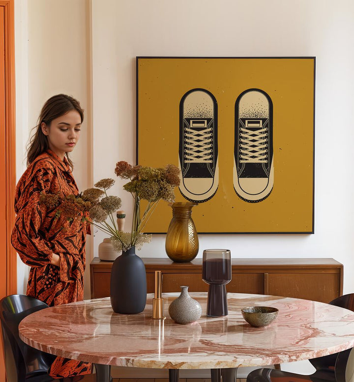 Stylish woman by a table with dried flowers, showcasing THE BLACK CHUCKS, FASHION POSTERS on the wall.