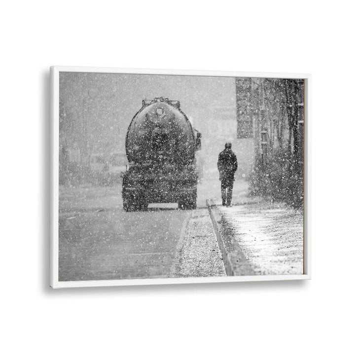 Black and white street scene featuring a person walking in snow alongside a truck, perfect for HEAVY THINGS, PHOTOGRAPHY PRINTS.