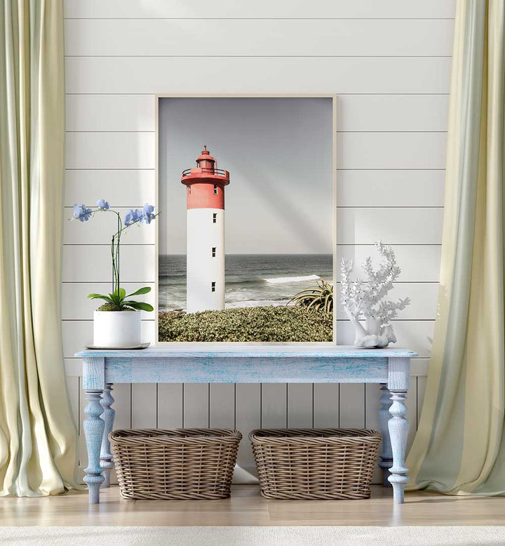 Framed lighthouse print over blue console with baskets — BEACON BY THE SEA , BEACH PAINTINGS