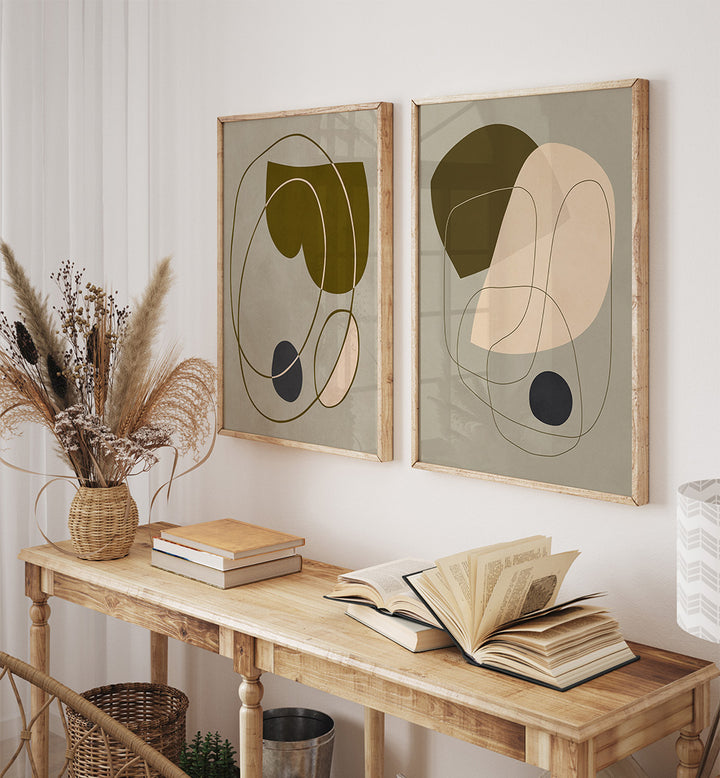 Two abstract framed artworks on a wall above a wooden console table with books and decor.