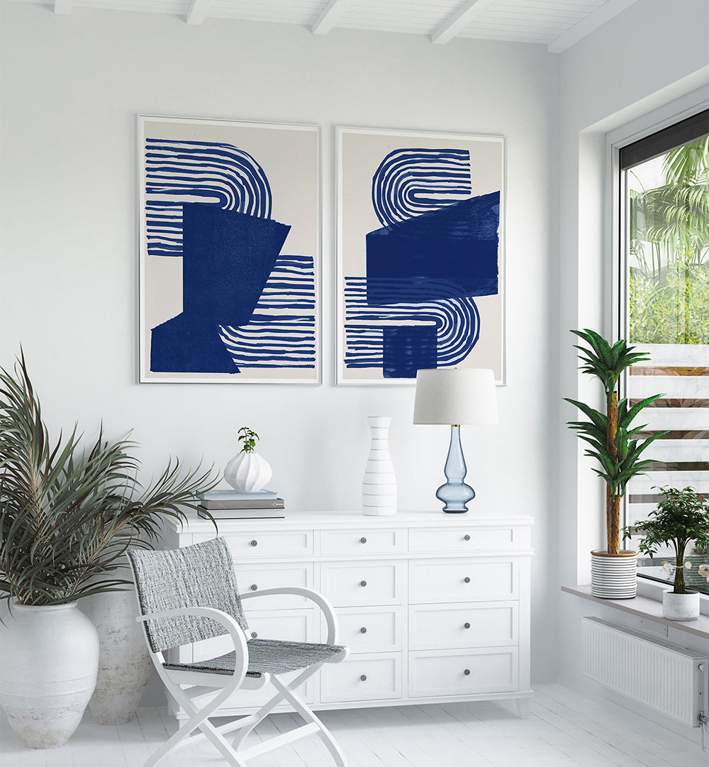 Modern interior with abstract blue artwork on a white wall, white furniture, and decorative plants.