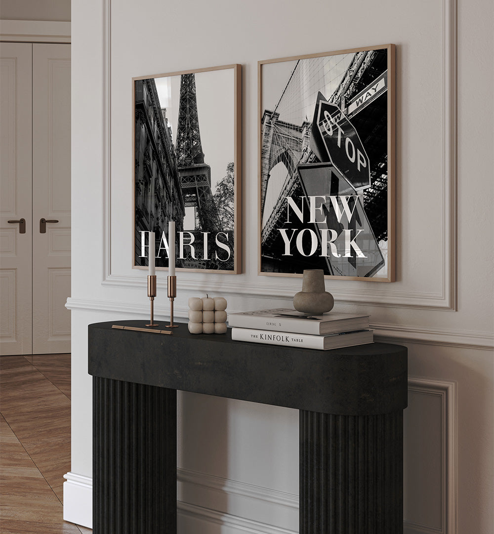 Two framed prints of the Eiffel Tower and a stop sign with 'New York' text on a wall above a black console table.