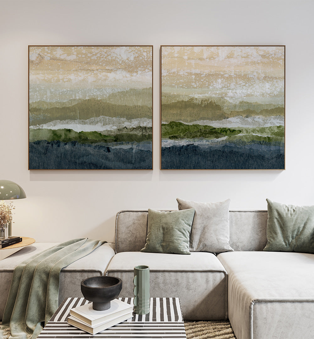 Two abstract landscape paintings above a gray sectional sofa in a living room.