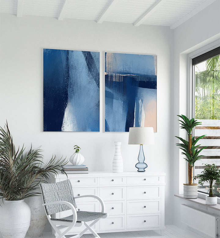 Modern interior with abstract blue artwork on a white wall, white furniture, and decorative plants.