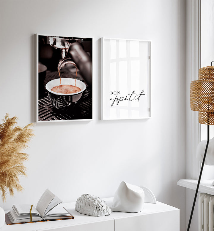 Two framed prints on a wall with a decorative lamp and books on a white surface.