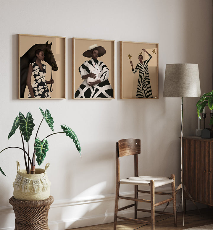 Three framed artworks on a wall with a chair, lamp, and plant in the foreground.