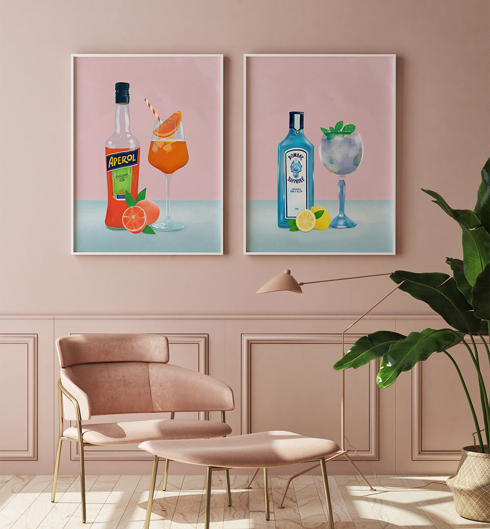 Two framed artworks of drinks on a pink wall with a chair and plant in the foreground.