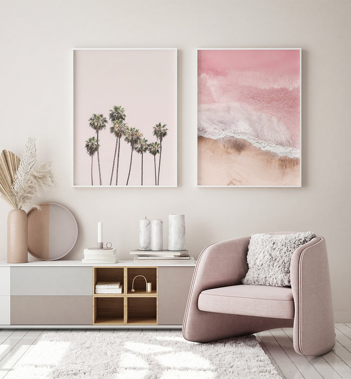 Modern living room with a pink armchair, decorative vases, and wall art of palm trees and beach.