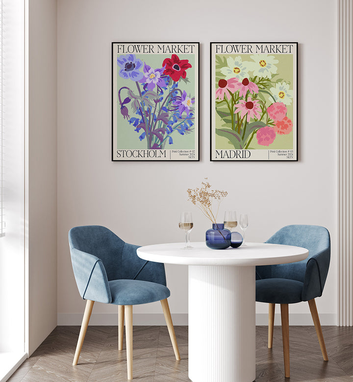 Dining area with two blue chairs, a white table, and floral-themed posters on the wall.
