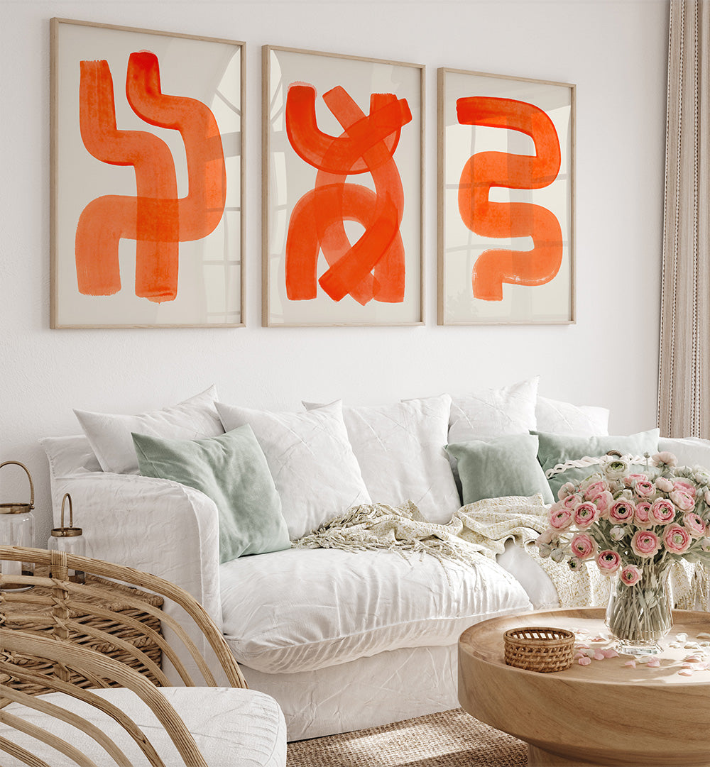 Living room with white sofa, abstract orange art, and a vase of pink flowers.