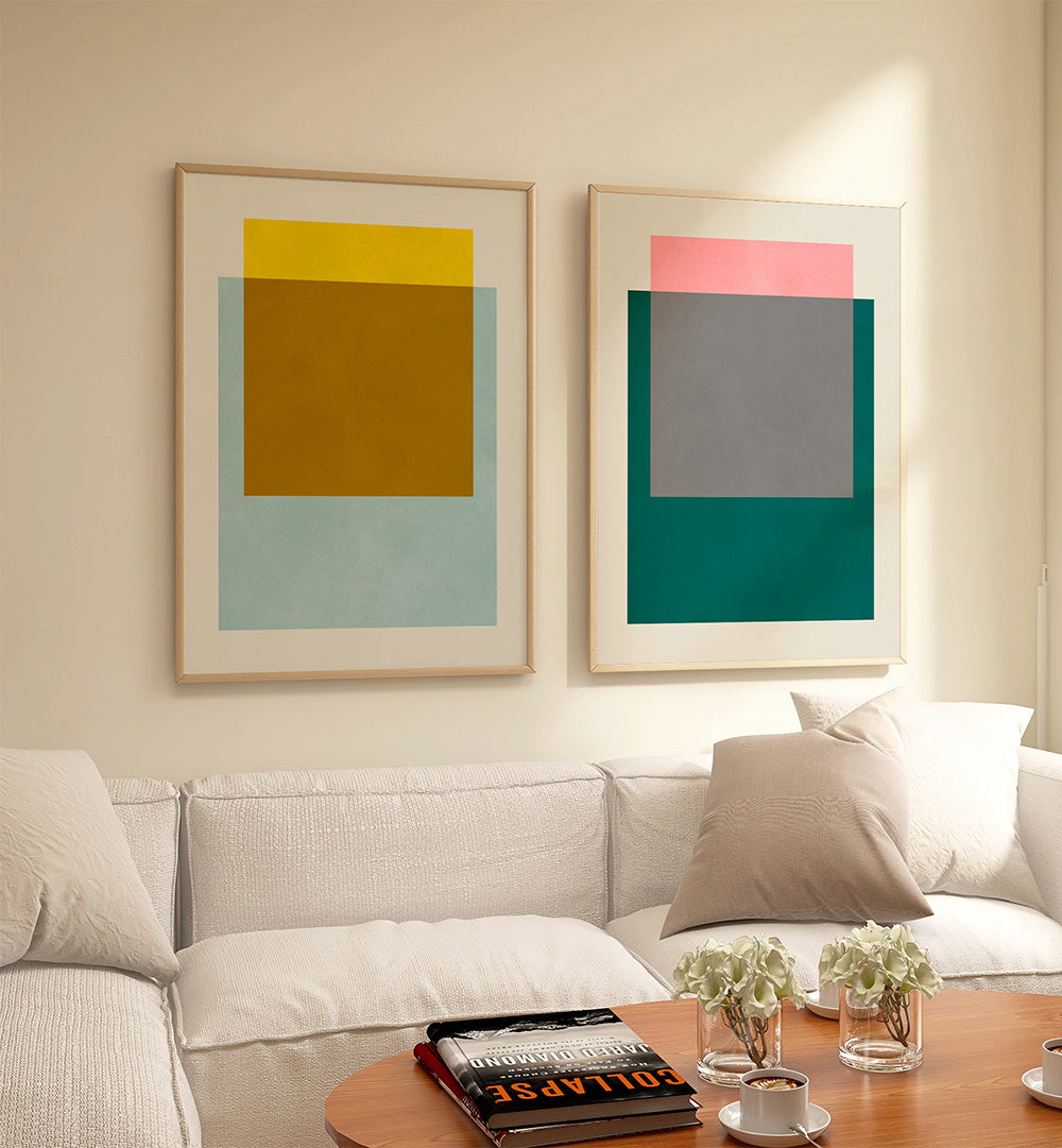 Two abstract art pieces on a wall above a sofa with a coffee table in the foreground.