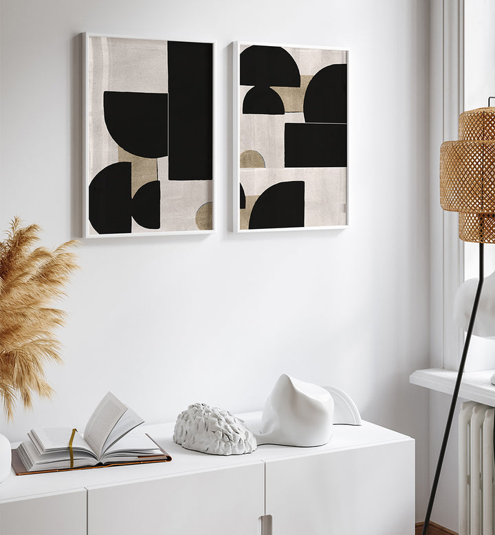 Two abstract art pieces on a wall above a white cabinet with decor items.