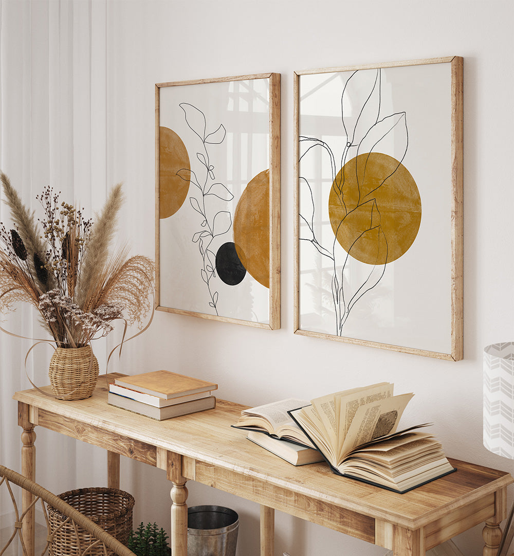 Two abstract wall art pieces with circular and line designs on a white wall above a wooden console table.