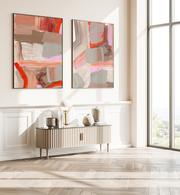 Two abstract paintings on a wall above a console table in a bright room with large windows.
