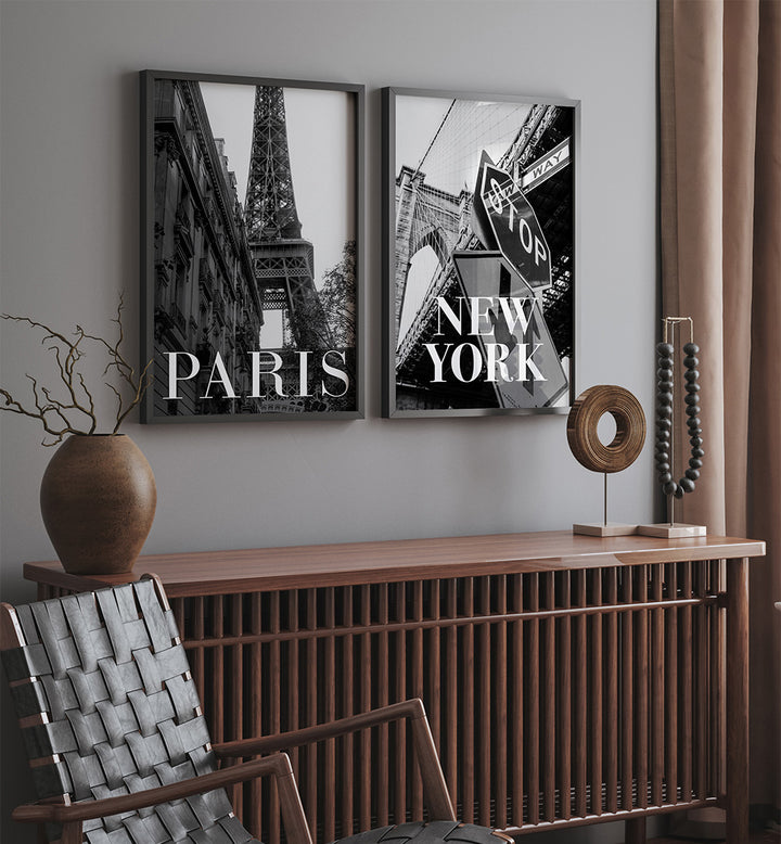 Two framed pictures of the Eiffel Tower and a New York street sign on a wall above a wooden console table.