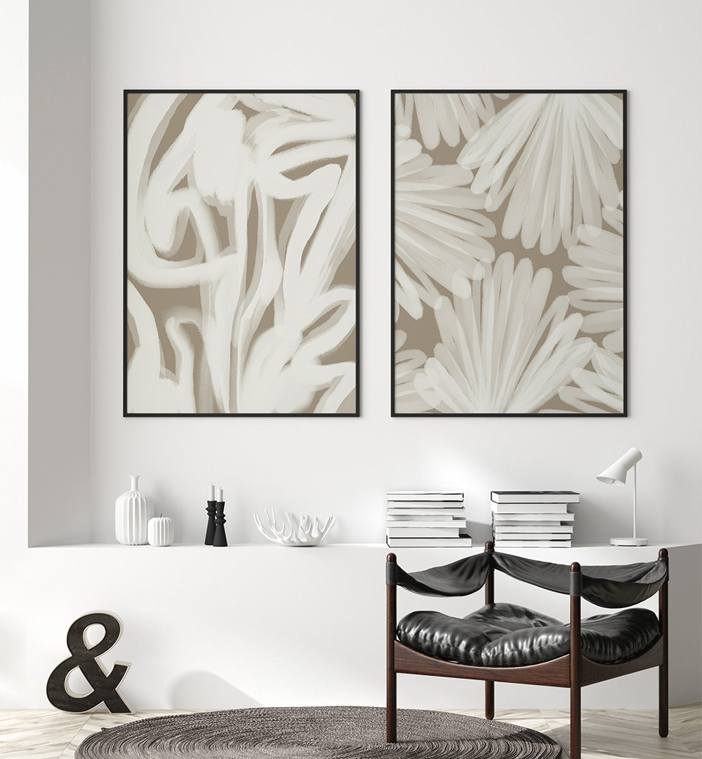Two abstract wall art pieces on a white wall above a console table with decor items.