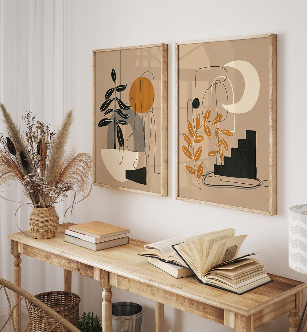 Two abstract art pieces on a wall above a wooden console table with books and a vase.