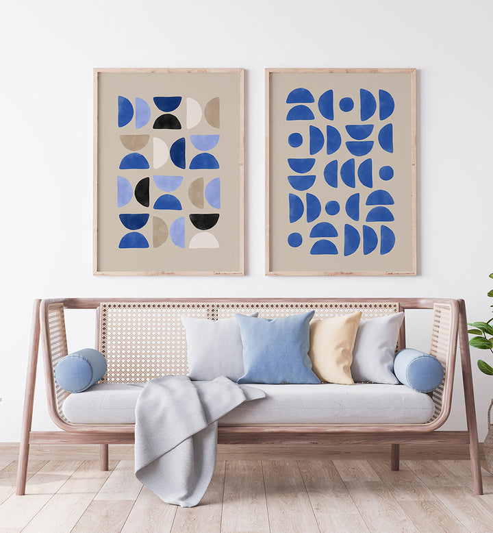 Wicker sofa with colorful cushions and two abstract art pieces on a white wall.