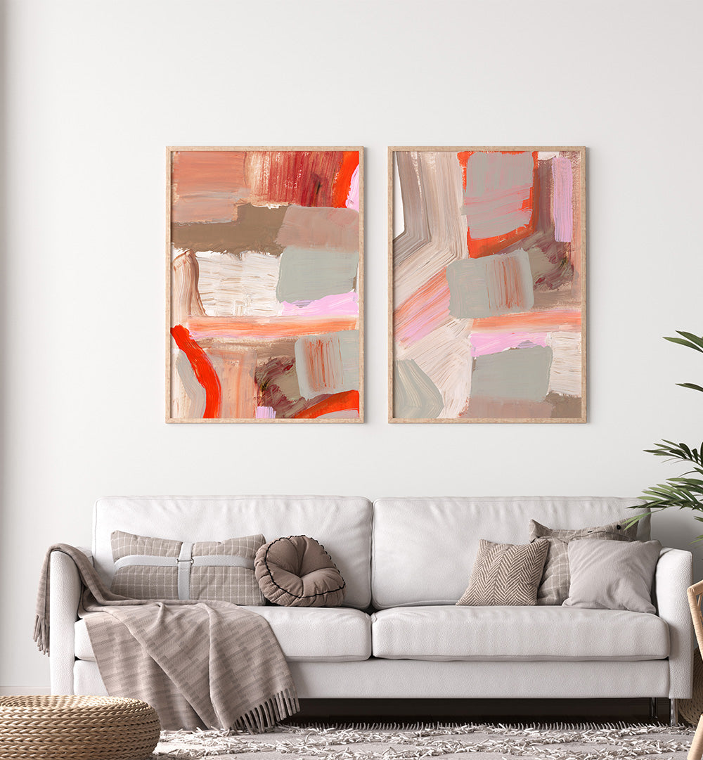 Two abstract art pieces on a wall above a white sofa with decorative pillows.