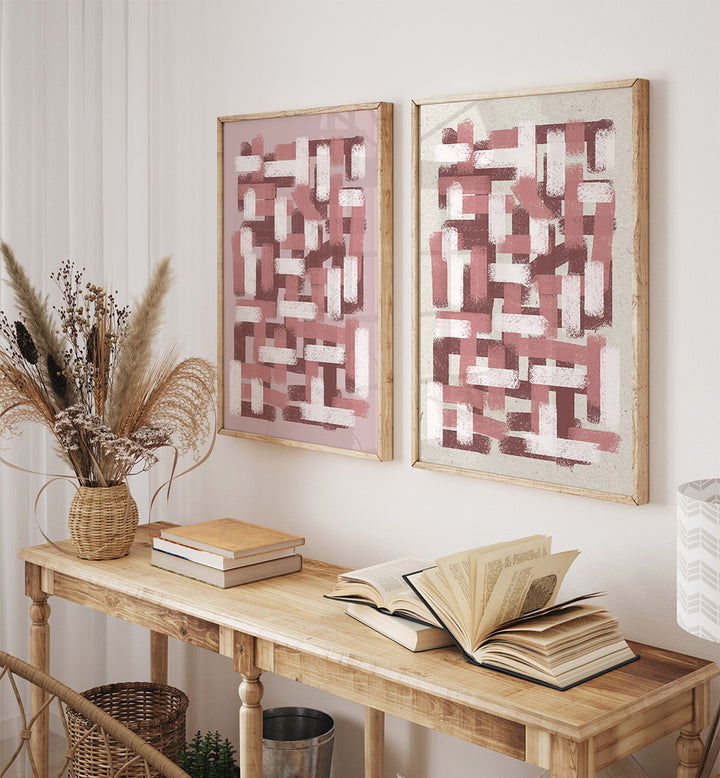 Two abstract paintings on a wall above a wooden console table with books and decor.