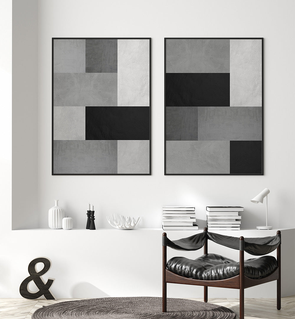 Two abstract art pieces on a wall above a table with books and decorative items.