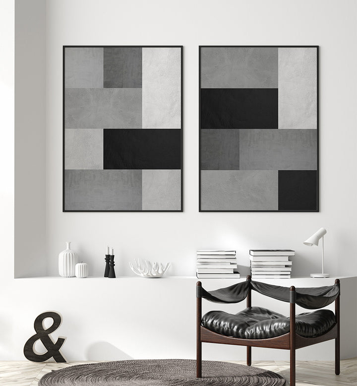 Two abstract art pieces on a wall above a table with books and decorative items.