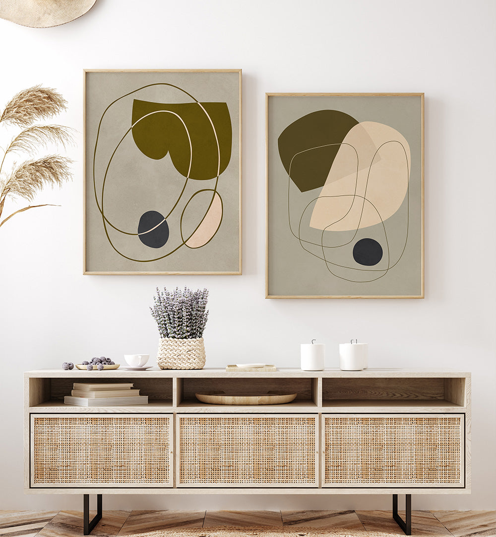 Two abstract art pieces on a wall above a wooden console table with decorative items.