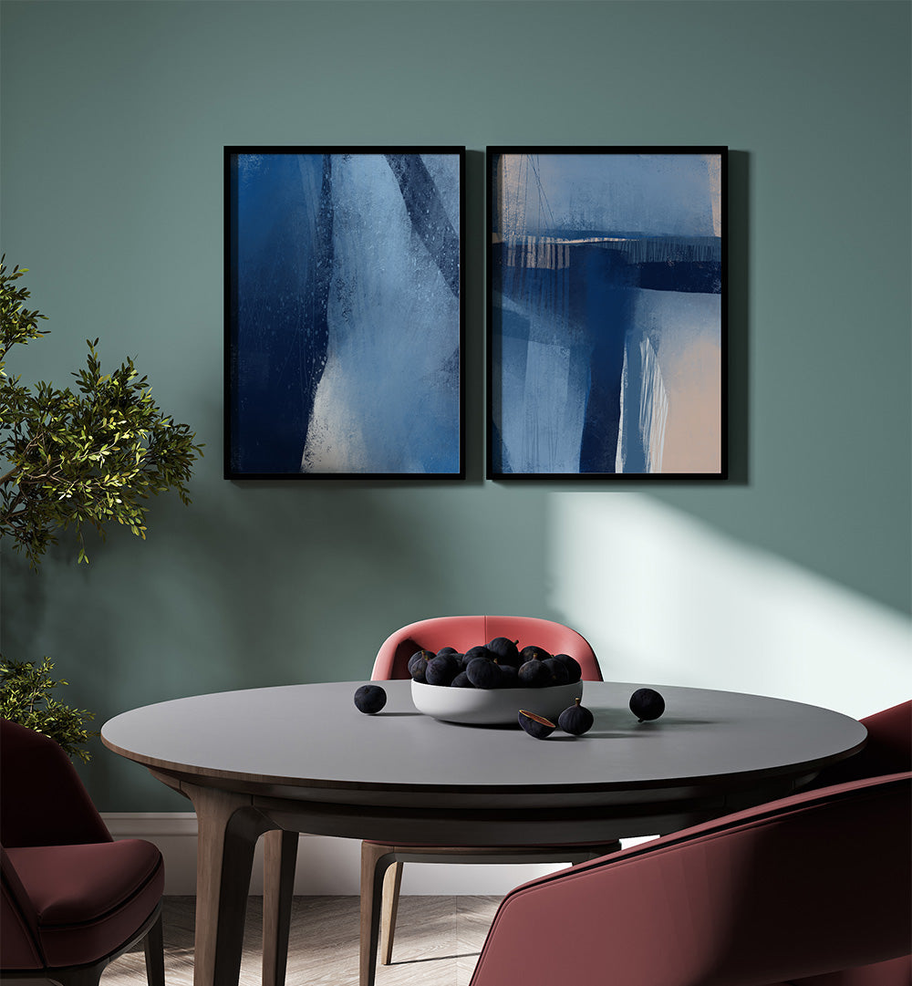 Two abstract paintings on a wall above a dining table with chairs.
