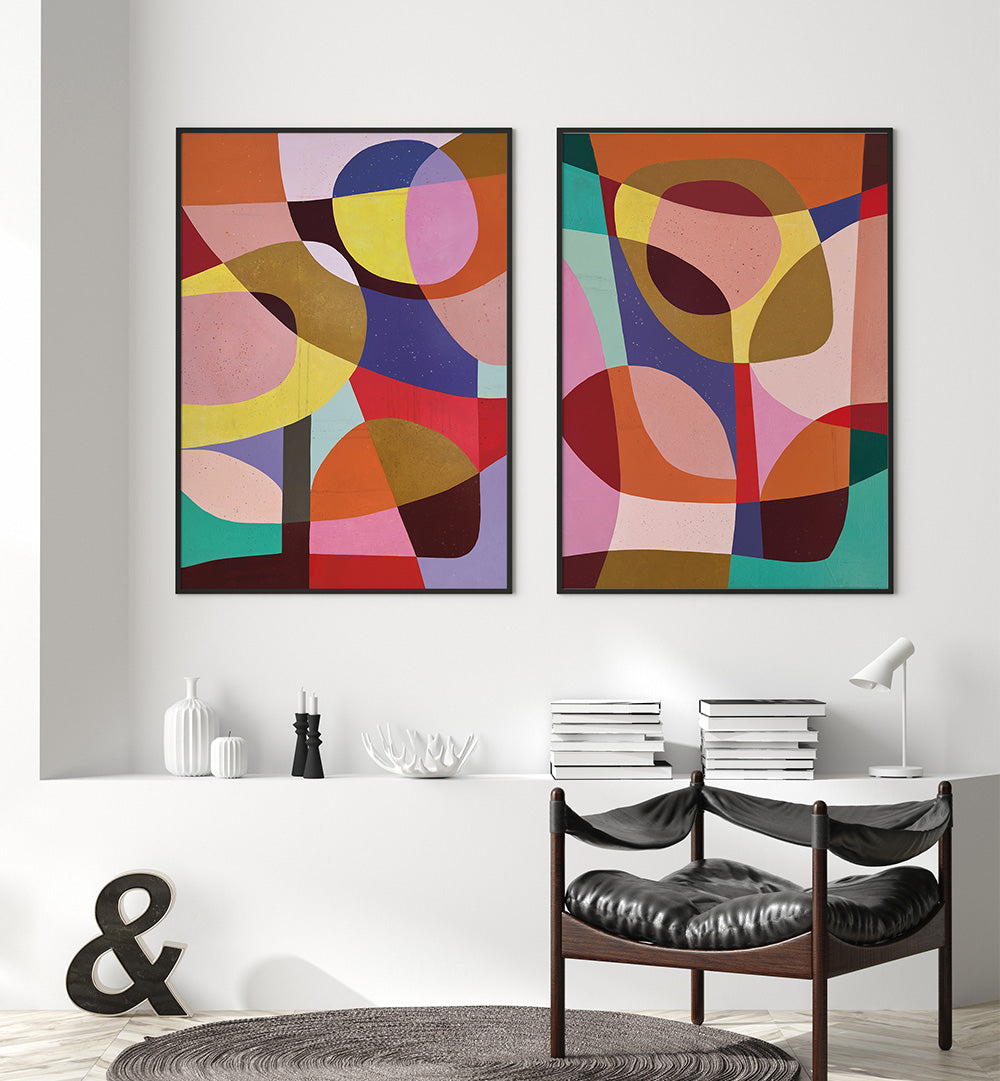 Two abstract art pieces hanging on a wall above a dining table.