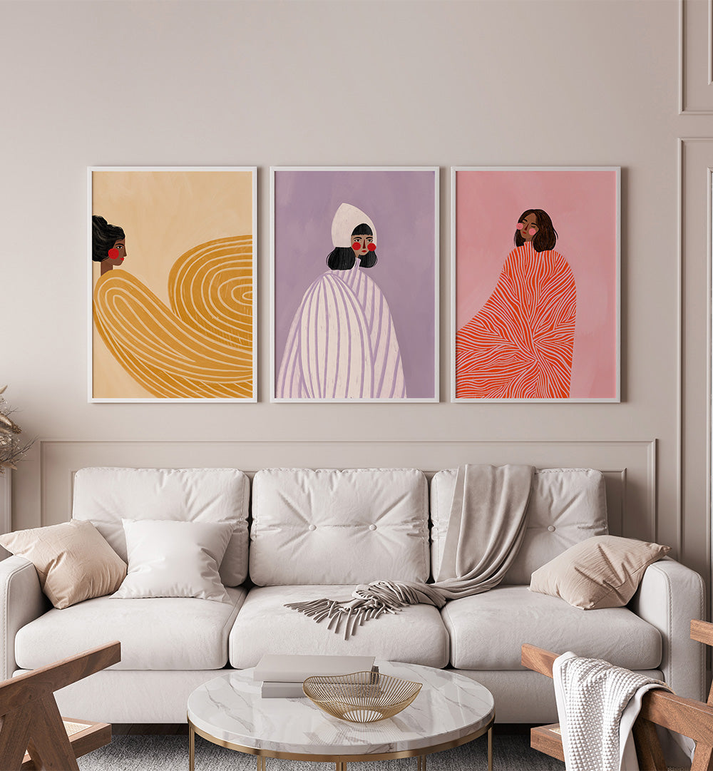 Three abstract art prints on a wall above a sofa in a living room.