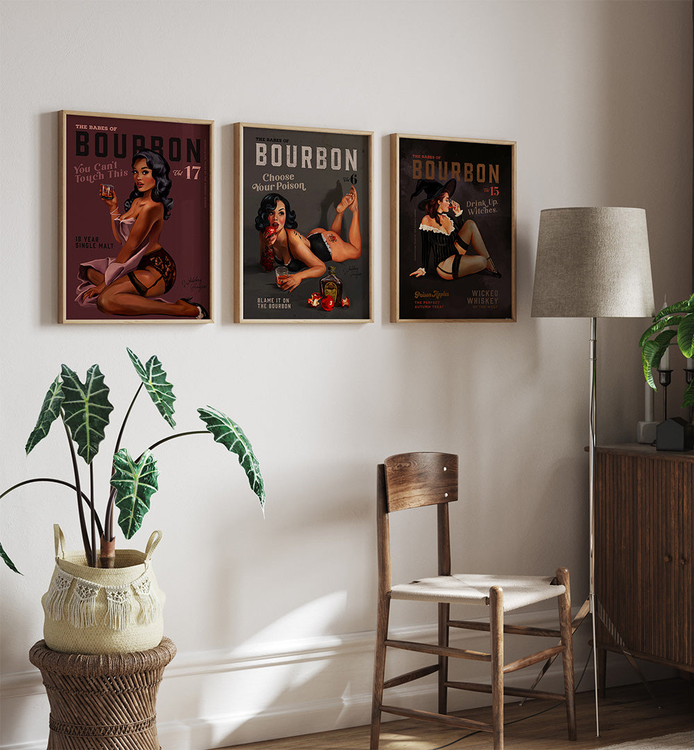Three framed posters of women with drinks on a wall above a chair and lamp.