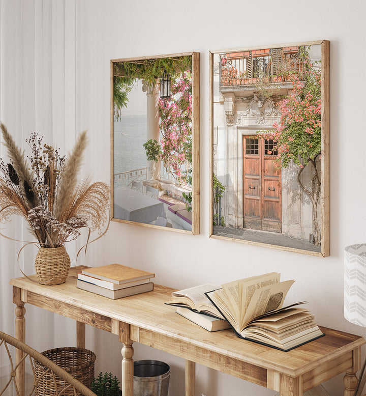 Two framed pictures on a wall above a wooden console table with books and a vase.