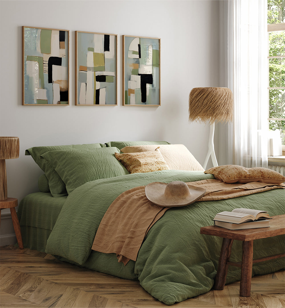 Bedroom with green bedding, abstract art, and wooden furniture.