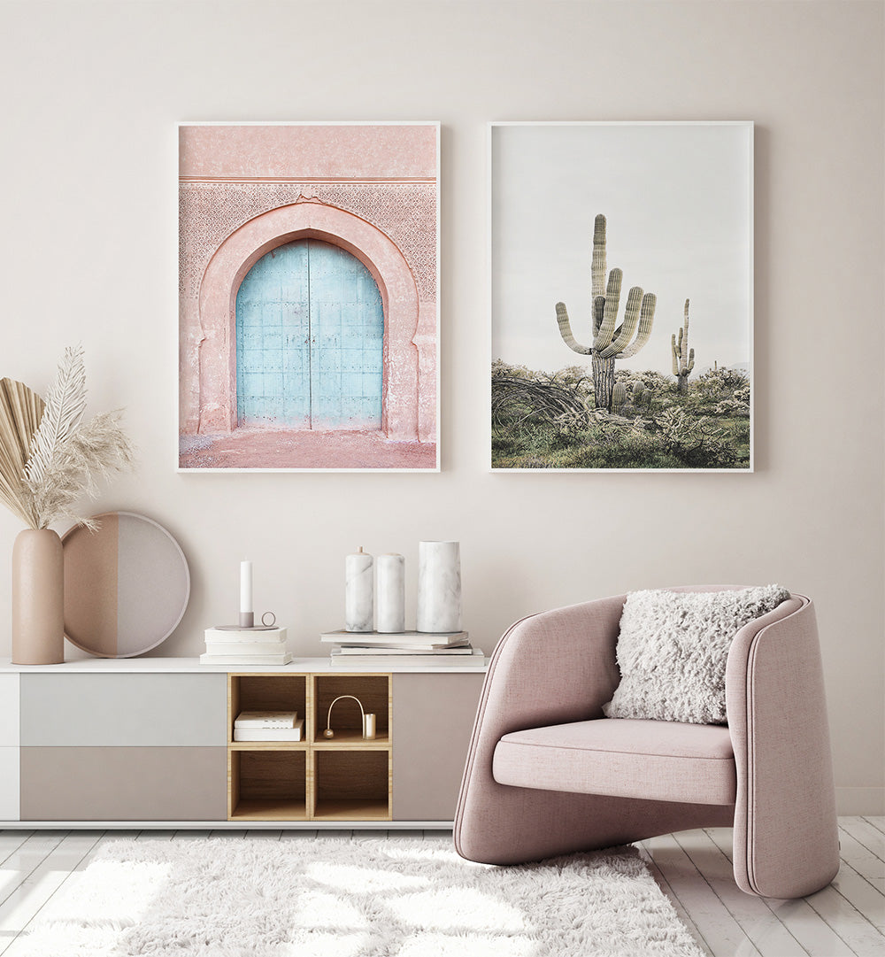 Modern living room with pink armchair, decor items, and wall art of a door and cacti.