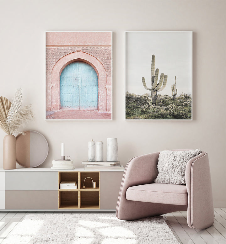 Modern living room with pink armchair, decor items, and wall art of a door and cacti.