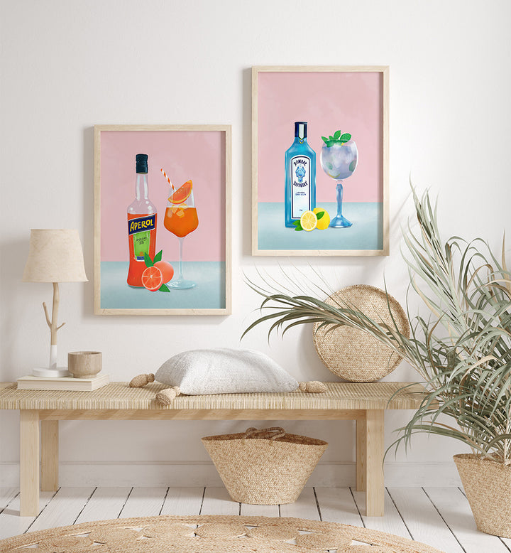 Two framed artworks of drinks on a wall above a wooden bench with decor items.