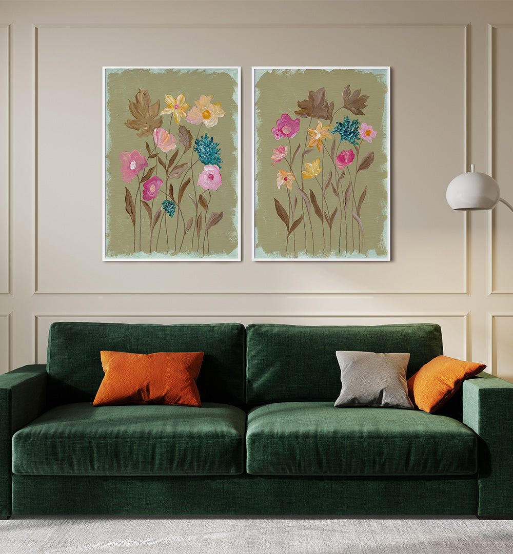Green sofa with orange and gray cushions in front of two floral wall art pieces.