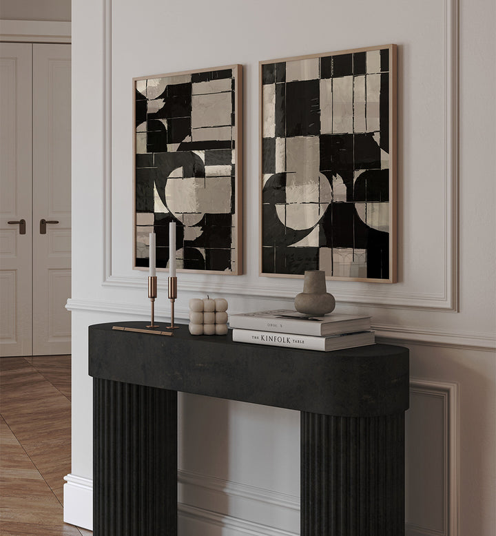 Two abstract art pieces on a wall above a black fireplace mantle with decorative items.