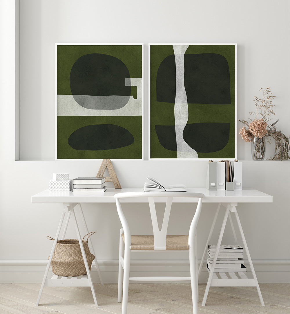 Two abstract art pieces on a wall above a white desk with books and decor.
