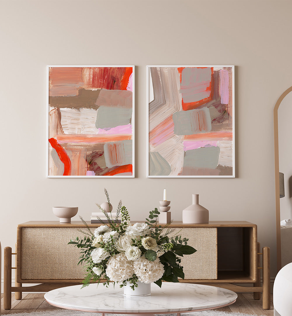 Two abstract paintings on a wall above a wooden console table with decorative items.