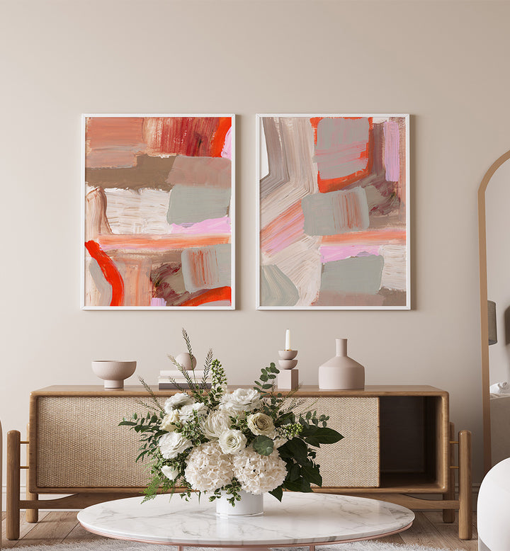 Two abstract paintings on a wall above a wooden console table with decorative items.