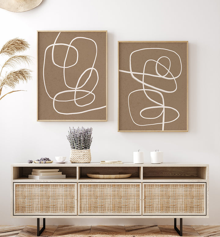 Two abstract wall art pieces on a white wall above a wooden console table.