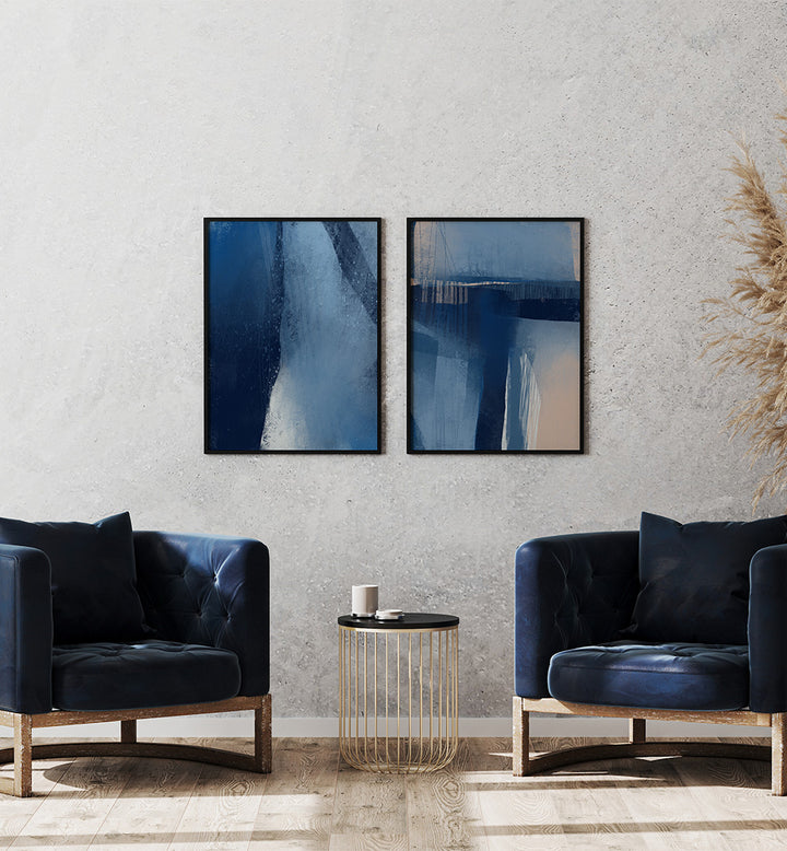 Modern living room with abstract blue artwork on a textured wall, two dark blue armchairs, and a small round table.