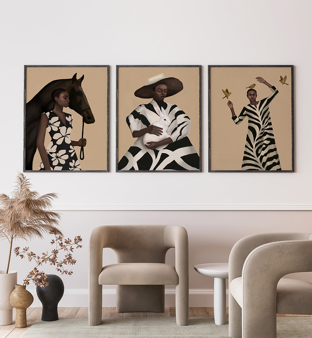 Three framed artworks of women in zebra-striped outfits on a wall above modern furniture.