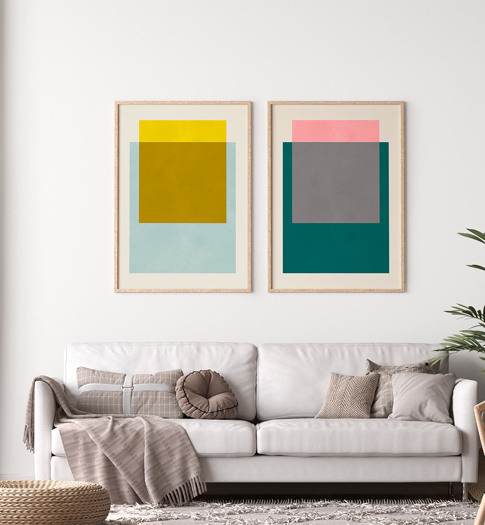 Two abstract art pieces on a wall above a white sofa with decorative pillows.