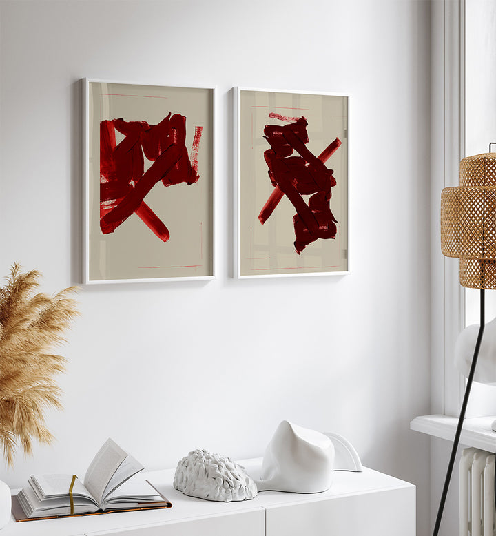Two abstract red artworks on a white wall with decorative elements below.